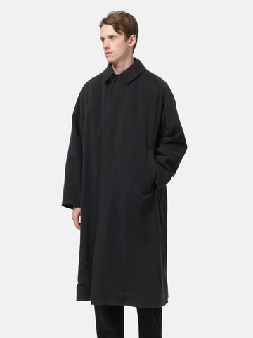 Model standing in studio wearing the A.PRESSE Maxi Length Washed Silk Balmacaan Coat in Black buttoned up