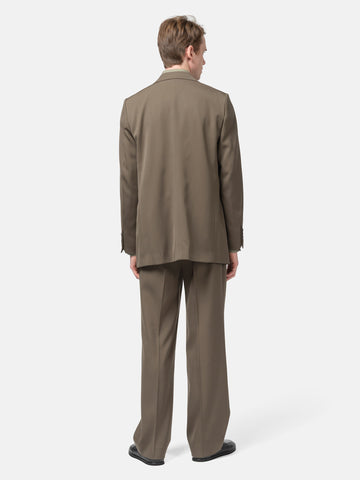 Rear view of the Model standing in studio wearing the AURALEE Light Wool Max Gabardine Two-Tuck Slacks Dark in Olive Brown