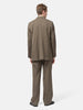 Rear view of the Model standing in studio wearing the AURALEE Light Wool Max Gabardine Two-Tuck Slacks Dark in Olive Brown