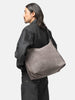 Side view of the model wearing the LEMAIRE Belted Hobo Bag Mink
