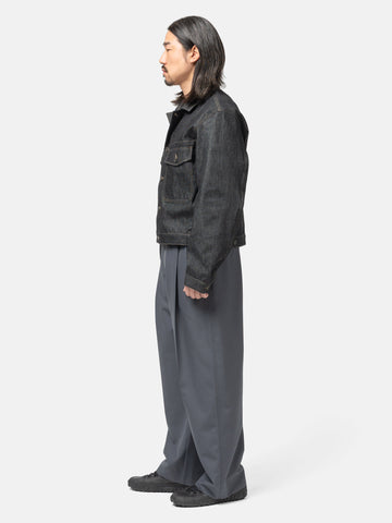Side view of the model wearing LEMAIRE Pleated Tailored Pants Carbon