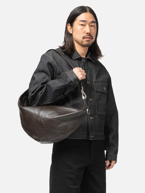 Three quarter view of the model wearing the LEMAIRE Quiver Clip Bag Dark Chocolate