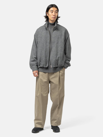 Model standing in studio wearing the wool light tweed zip-up blouson from URU.