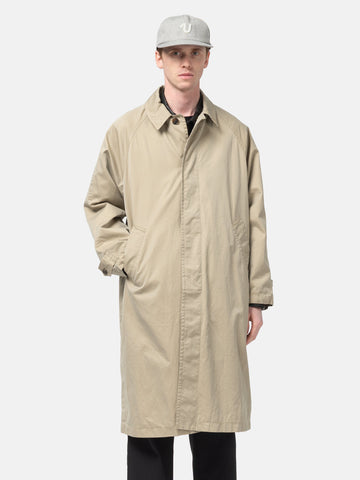 Half body shot of the Model standing in studio wearing the UNLIKELY Balmacaan Coat in Beige buttoned up