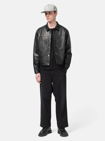 Model standing in studio wearing the UNLIKELY Skater's Work Pants in Black