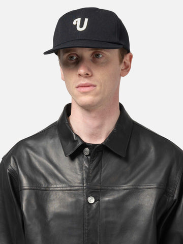 Shot in studio of the UNLIKELY Team Cap in Black worn by the model