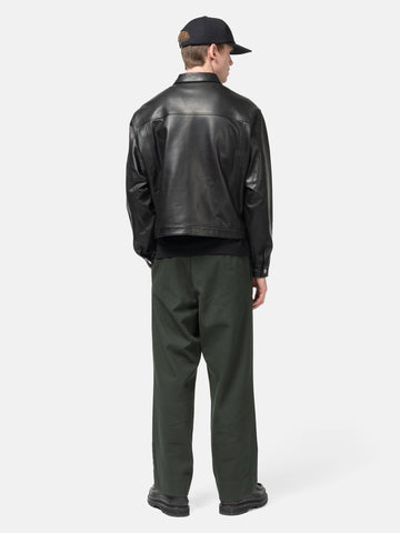 Rear view of the Model standing in studio wearing the UNLIKELY Zero Leather Trucker JKT in Black