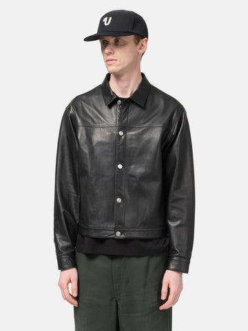 Half body shot of the Model standing in studio wearing the UNLIKELY Zero Leather Trucker JKT in Black