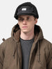 Model is wearing WTAPS AVT Cap  Nylon Satin Cordura in Black with ear flap attached