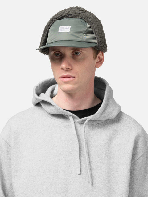 Model is wearing WTAPS AVT Cap Nylon. Satin in Cordura Olive Drab with ear flap attached