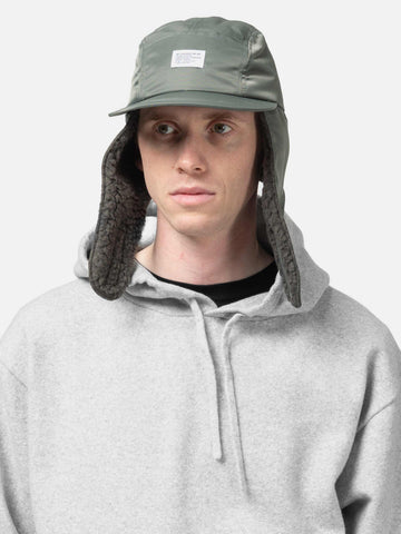 Model is wearing WTAPS AVT Cap Nylon. Satin in Cordura Olive Drab with the ear flap down