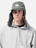 Model is wearing WTAPS AVT Cap Nylon. Satin in Cordura Olive Drab with the ear flap down