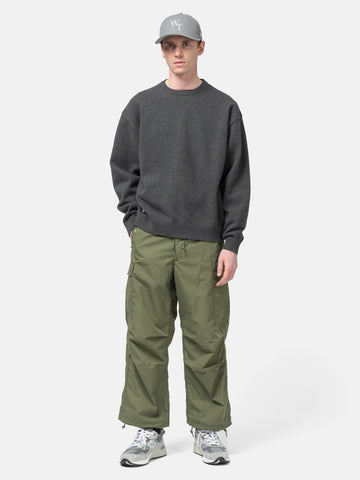 Model standing in studio wearing the WTAPS Crewneck Sweater in NYCO Black