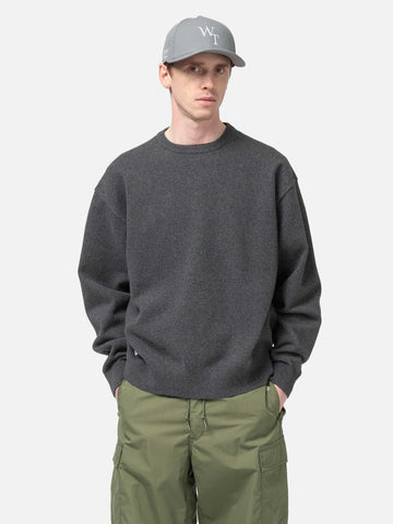 Half body shot of the Model standing in studio wearing the WTAPS Crewneck Sweater in NYCO Black