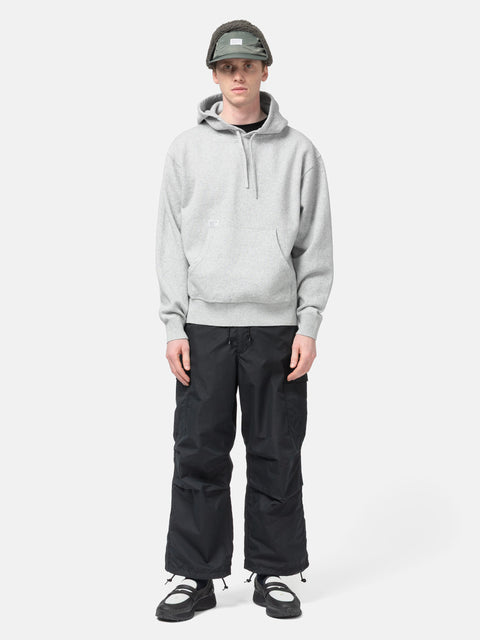 Model standing in studio wearing the WTAPS Hoodie Sweater in NYCO Gray
