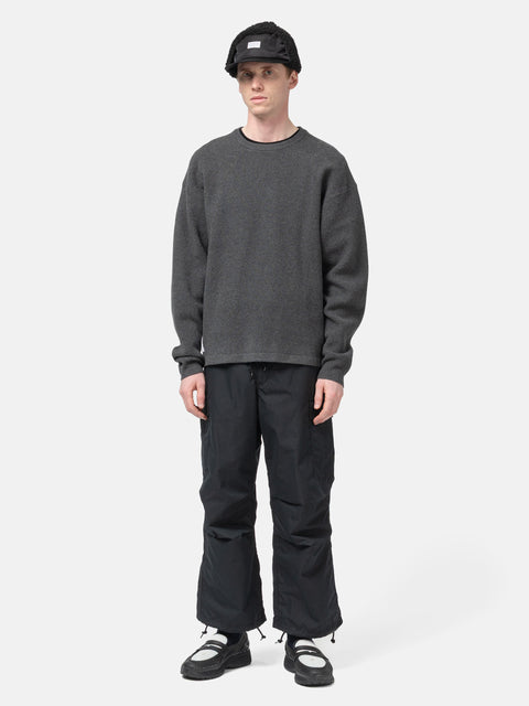 Model standing in studio wearing the WTAPS KRS UPR Sweater in NYCO Black