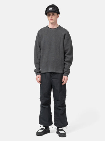 Model standing in studio wearing the WTAPS KRS UPR Sweater in NYCO Black
