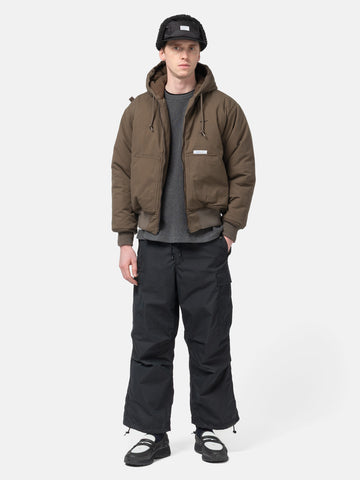 Model standing in studio wearing the WTAPS MILT9601 Trousers NYCO in Weather Black