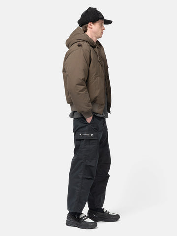 Side view of the Model standing in studio wearing the WTAPS MILT9601 Trousers NYCO in Weather Black
