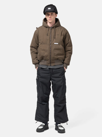Model standing in studio wearing the WTAPS Puff Doom Jacket in Cotton Weather Brown