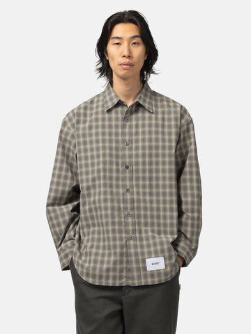 half body shot of the model wearing the WTAPS Txt 01 / LS / Poly. Broadcloth. Textile. Of Olive Drab